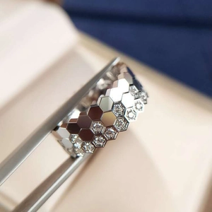 Macro shot of silver honeycomb ring set with zircon pavé detail held by tweezers
