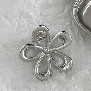 Macro view of silver floral hair claw clip with metallic mirror finish and spring detail