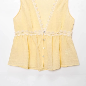 Sleeveless yellow V-neck top with white lace trim and button-up front detail