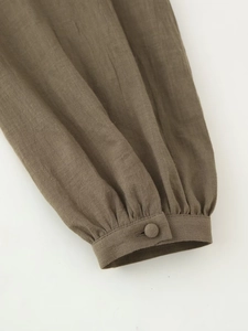 Detail of dark brown linen shirt sleeve with pleated cuff and matching fabric button