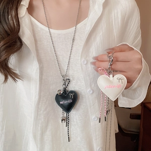 Macro view of heart leather pendant with silver bow detail and engraved logo on necklace