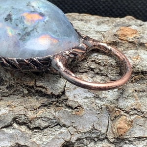 Macro detail of retro bronze Labradorite pendant with natural blue flash on wood bark