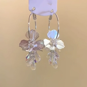 Boucles d'oreilles fleurs argentées avec pampilles en cristal sur carte de présentation