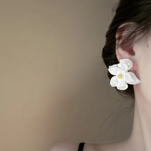Close-up of elegant white lace flower stud earrings worn by a model in profile