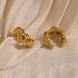 Detailed macro view of 18K gold plated bamboo texture ear clips on champagne silk fabric