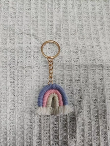 Detailed macro view of handmade woven rainbow keychain with cotton tassels and gold ring