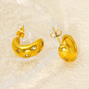 Detailed macro view of gold-plated C-shaped stainless steel earrings with sparkling crystals