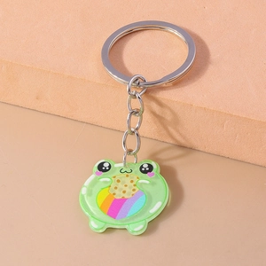 Detail of cute acrylic green frog keychain holding a cookie with rainbow pattern design