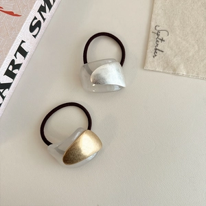 Detailed macro view of minimalist hair ties with gold and silver matte metal accents