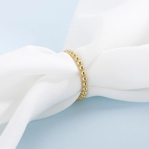 Détail d'une bague à perles dorées sur soie blanche élégante avec fond bleu clair