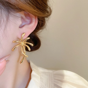 Close-up of gold plated floral metal stud earring worn on a model's ear