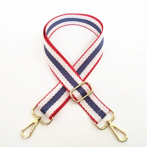 Close-up of red, white and blue striped canvas bag strap with golden metal clasps