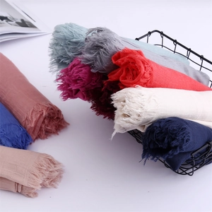 Pastel cotton linen scarves with fringe edge neatly arranged in a metal storage basket
