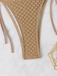 Detail of khaki popcorn fabric bikini bottom with side ties on marble background