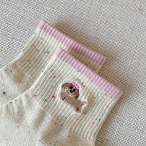 Detail of dachshund embroidery on off-white knit socks with colorful flecks and pink cuffs