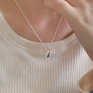 Macro shot of silver teardrop pendant necklace on neck for minimalist elegant styling