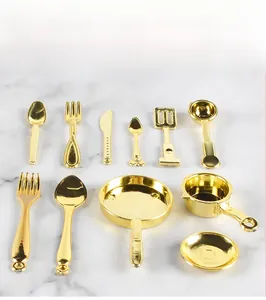 Detailed top view of a mini golden kitchenware set including pots and cutlery on marble