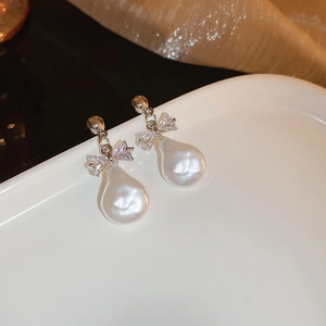 Vue macro des boucles d'oreilles en argent avec nœud en cristal et perle baroque