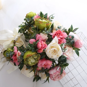 Detail view of floral crown with pink and ivory roses, green leaves and white ribbon