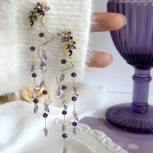 Vue détaillée de longues boucles d'oreilles papillon violettes avec des cristaux.