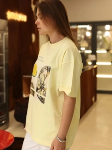 Γυναικείο κίτρινο βαμβακερό t-shirt με στάμπα στρείδι και λεμόνι σε καφέ περιβάλλον