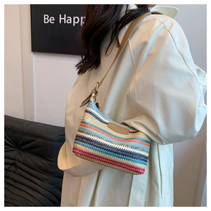 Detail of colorful striped woven straw shoulder bag with brown leather strap and logo patch