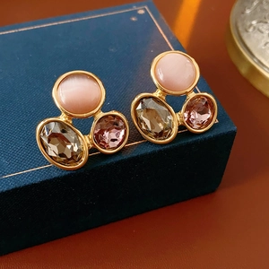 Close-up of vintage oval earrings with cat eye stones and colorful crystals on a jewelry box