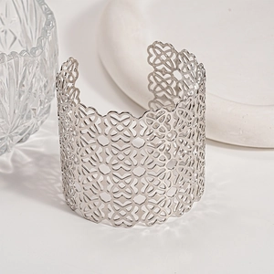 Dettaglio macro del motivo floreale geometrico traforato argento su bracciale rigido