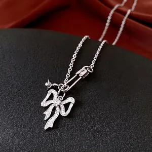 Silver bow necklace with zircon clip pendant on an elegant black textured background