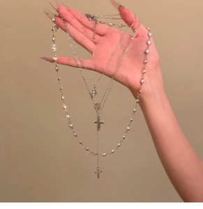 Detail einer mehrlagigen Kreuzkette mit Perlen und religiösen Medaillen für Damen