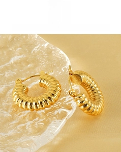 Macro shot of 18k gold plated chunky spiral earrings with textured wave pattern on glass
