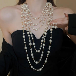 Detail of multi-layer long pearl necklace and earrings set on elegant black dress