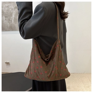 Detail of strawberry print on brown corduroy tote bag worn by a model from the back