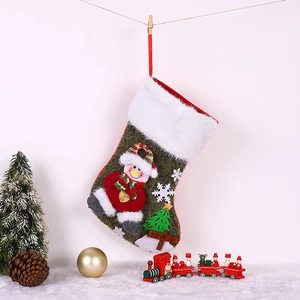 Détail d'une chaussette de Noël verte avec bonhomme de neige 3D et bordure en fourrure
