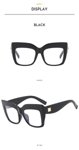 Detail view of large black frame glasses featuring elegant gold square metal hinge accents