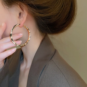 Detail of large gold-edged hoop earrings with black and white texture on a female model