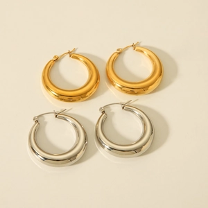 Top view of gold and silver thick hollow hoop earrings on a clean beige background