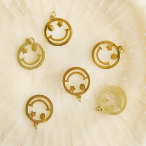 Golden hollow smiley face pendants with star eyes on a textured white background