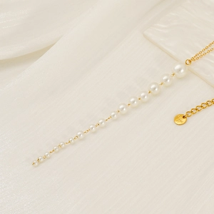 Macro détaillée d'un collier en acier inoxydable doré avec d'élégants glands en perles