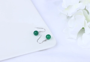 Detailed view of green agate beads on S925 silver hooks placed on a white ceramic plate