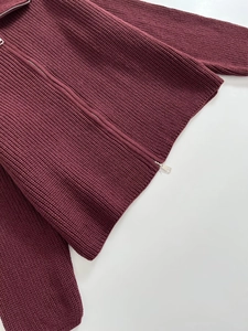 Dettaglio della maglia pesante bordeaux e doppia cerniera in argento sul cardigan