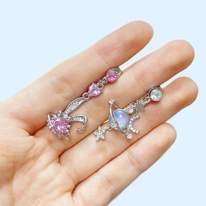 Detailed shot of pink heart moon and silver planet navel rings held by hand