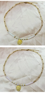 Detail of 18k gold monstera leaf pendant with handmade beads on paperclip chain