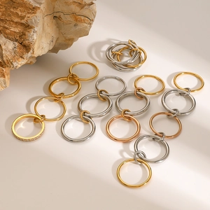 Detail view of stacked stainless steel rings in gold, silver, and rose gold with stones