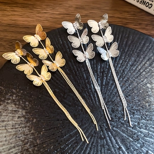 Detail view of gold and silver butterfly tassel earrings with cubic zirconia on black tray
