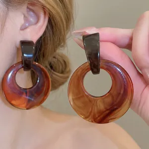 Retro geometric amber resin hoop earrings with a tortoiseshell texture on female model