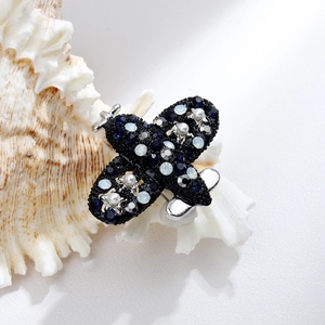 Detail of a crystal airplane brooch with blue rhinestones on a white shell background