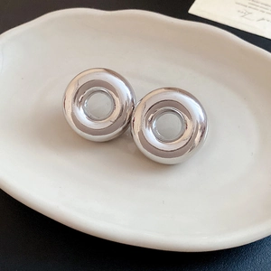 Detailed view of silver C-shaped hoop earrings on a decorative ceramic tray