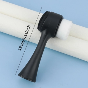 Detail of double-sided black facial brush with soft bristles and silicone massage pad