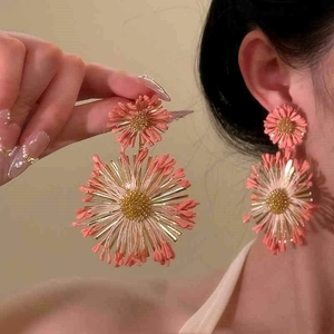 Close-up of pink layered flower earrings with gold centers worn by a fashion model